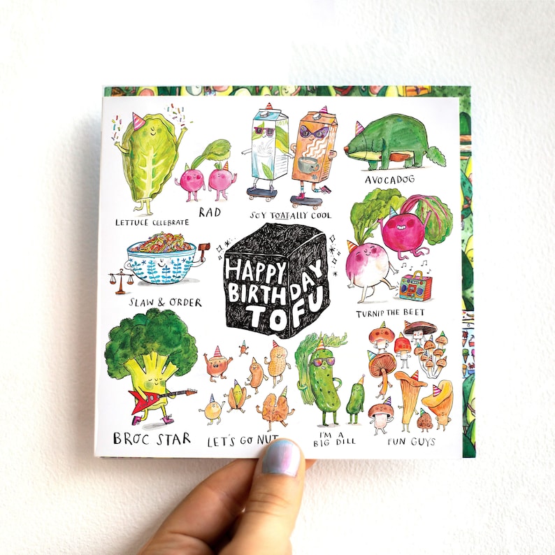 K&ouml;nnte beinhalten: Eine wei&szlig;e Karte mit einer bunten Illustration verschiedener Gem&uuml;se und Fr&uuml;chte mit Gesichtern und Partyh&uuml;ten. Der Text "Happy Birthday Tofu" befindet sich in einem schwarzen Kasten in der Mitte der Karte.
