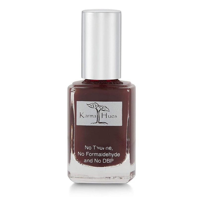 May include: A bottle of Karma Hues nail polish in a deep burgundy color. The bottle has a silver cap and a label that says "Karma Hues" and "No Toulene, No Formaldehyde and No DBP".