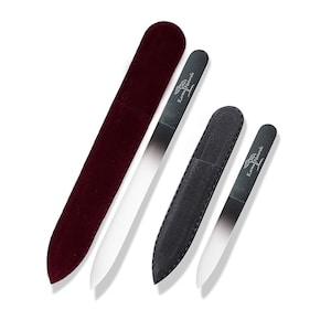 May include: Two glass nail files with protective velvet cases. The larger file is in a burgundy case and the smaller file is in a black case. Both files have the text "Karma Naturals" printed on them.