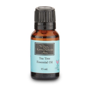 May include: A brown glass bottle with a black cap containing Tea Tree Essential Oil. The bottle is labeled with the brand name Karma Naturals and the volume is 15 ml. The label is light blue with white text and a small pink heart.