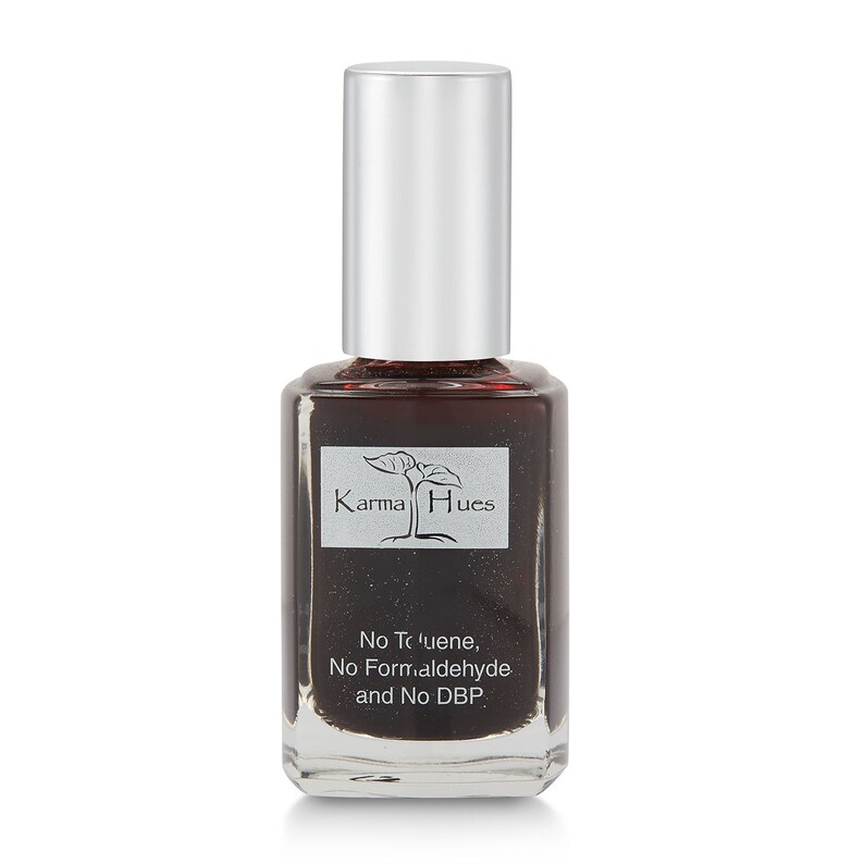 May include: A clear glass bottle of Karma Hues nail polish in a dark brown color with a silver cap. The bottle has a label with the brand name and the text "No Toluene, No Formaldehyde and No DBP."
