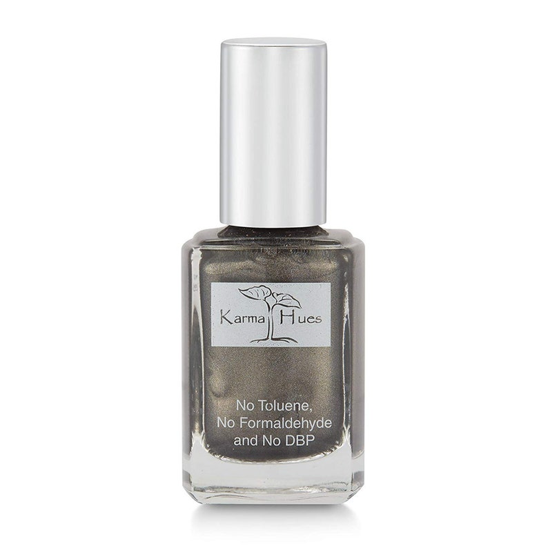 May include: A bottle of Karma Hues nail polish in a metallic silver color. The bottle is clear glass with a silver cap. The label says "Karma Hues" and "No Toluene, No Formaldehyde and No DBP".
