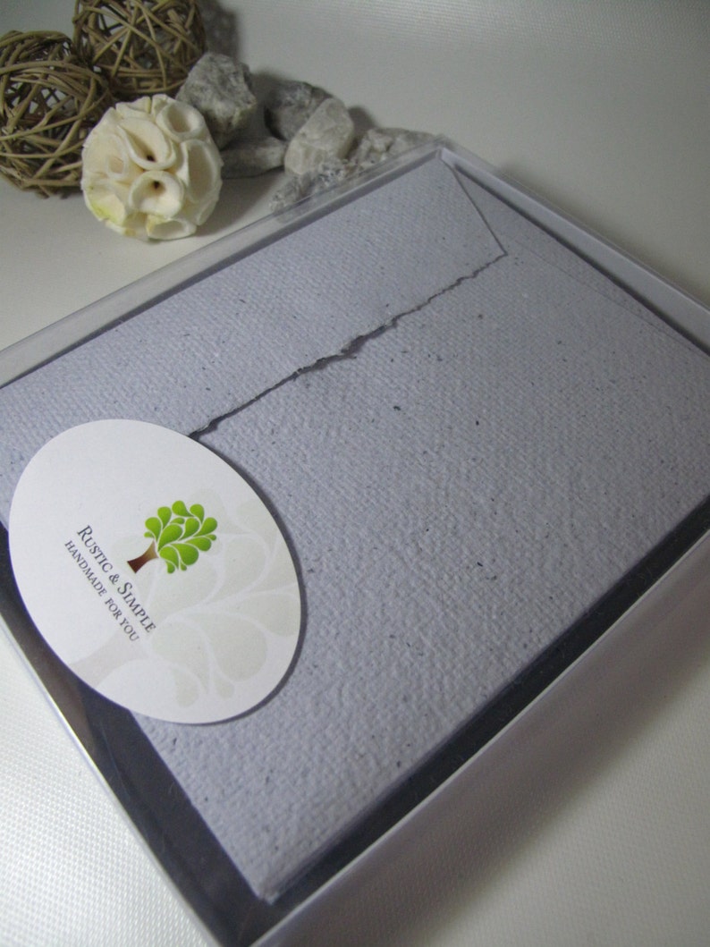 May include: A light purple envelope with a textured surface, packaged in a clear plastic box. The envelope has a white oval sticker with a green tree and the text "Rustic & Simple Handmade for You".