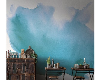 May include: A teal blue watercolor wall mural with a faded, light blue gradient. The mural is in a room with a wooden cabinet and two black metal tables with wooden tops and chairs.