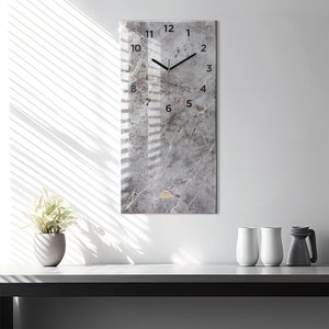 May include: A gray and white marble-patterned clock with black hands and black numbers. The clock is rectangular and has a modern design.
