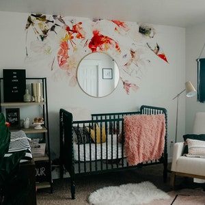 May include: A nursery room with a black crib, a white rocking chair, a black shelf with a sign that says "Welcome Home", and a floral wall decal.