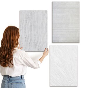 May include: Three white textured wall art panels. One panel has vertical wavy lines, another has horizontal lines, and the third has a marbled pattern. The panels are rectangular and vary in texture.