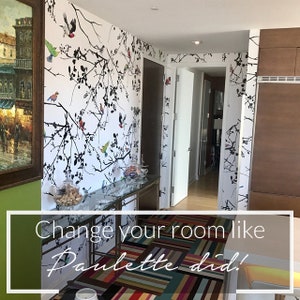 May include: A hallway with a white wall featuring a black and white wallpaper design with colorful birds. The floor is covered with a colorful striped rug. The text "Change your room like Palette did!" is written on the rug.