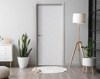 May include: A white door with a textured surface, a white floor lamp with a white lampshade, a potted snake plant, and a white dresser with drawers.