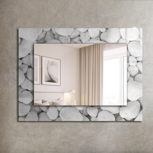 May include: A rectangular mirror with a white pebble border. The mirror reflects a room with white walls, a bed with white linens, and a window with white curtains.