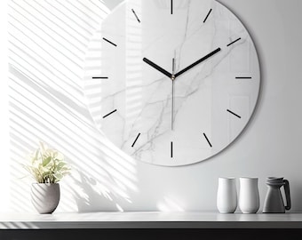 May include: A round wall clock featuring a white marble pattern with grey veining. The clock face has thin black hour markers and two black hands. The design is clean and circular, providing a clear display of time without any numbers.