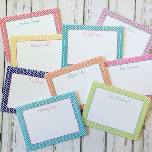 May include: A collection of personalized stationery cards with various names written on them. Each card has a white center with a colorful patterned border in shades of pink, blue, green, orange, and yellow.