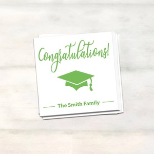 Puede incluir: Tarjeta blanca con texto verde que dice "&iexcl;Felicidades!" y un gorro de graduaci&oacute;n verde. La tarjeta tambi&eacute;n tiene el texto "The Smith Family" en negro.