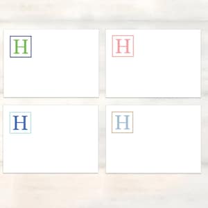 May include: Four white cards with a single letter 'H' in a square on each card. The squares are outlined in different colors: blue, green, pink, and gold. The letters are in different colors: green, blue, pink, and blue.