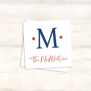 K&ouml;nnte beinhalten: Wei&szlig;e Karte mit einem blauen Gro&szlig;buchstaben "M", umgeben von zwei roten Punkten. Der Text "The McAllisters" ist in roter Kursivschrift unter dem Buchstaben geschrieben.