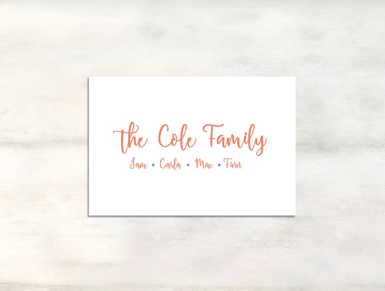 May include: A white card with the text "The Cole Family" in orange cursive lettering. Below the text are the names "Sam, Carla, Mac, Finn" in smaller orange lettering.