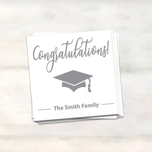 Puede incluir: Tarjeta blanca con texto gris que dice "&iexcl;Felicidades!" y un gorro de graduaci&oacute;n gris. La tarjeta tambi&eacute;n tiene el texto "The Smith Family" en gris.