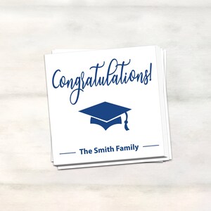 Puede incluir: Tarjeta blanca con texto azul que dice "&iexcl;Felicidades!" y un gorro de graduaci&oacute;n azul. La tarjeta tambi&eacute;n tiene el texto "The Smith Family" en azul.