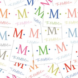 K&ouml;nnte beinhalten: Eine Sammlung wei&szlig;er Karten mit dem Text "The McAllisters" und einem einzelnen Buchstaben "M" in verschiedenen Farben, darunter Rot, Blau, Gr&uuml;n, Pink und Gelb. Jeder Buchstabe ist von zwei kleinen Punkten umgeben.