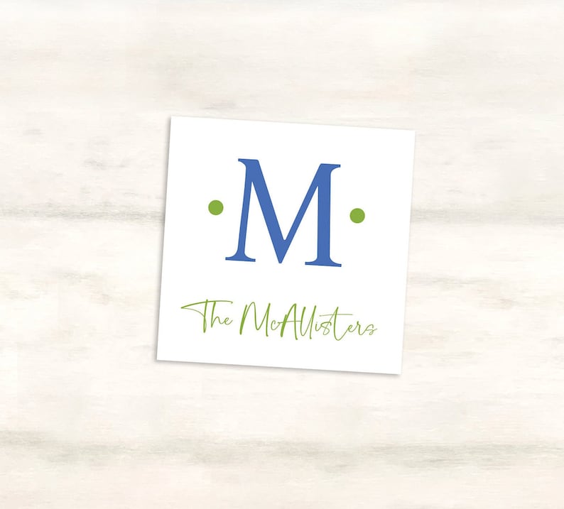 K&ouml;nnte beinhalten: Eine wei&szlig;e Karte mit einem blauen "M" umgeben von zwei gr&uuml;nen Punkten. Der Text "The McAllisters" ist in gr&uuml;ner Kursivschrift unter dem Buchstaben geschrieben.