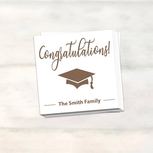Puede incluir: Tarjeta blanca con texto marr&oacute;n que dice "&iexcl;Felicidades!" y un icono de gorro de graduaci&oacute;n marr&oacute;n. Debajo del texto hay una l&iacute;nea que dice "The Smith Family".