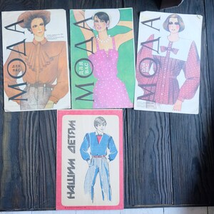 May include: Three vintage magazine covers with the word "MOAA" printed in large letters. The covers feature illustrations of women wearing different styles of clothing. The text on the covers reads "Dlya Vas" which translates to "For You".