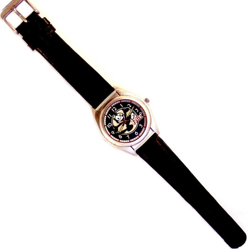 May include: A black leather wristwatch with a silver case and a black face. The face features a cartoon character with the word "BOING" printed on it.