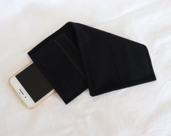 May include: A black fabric phone case with a velcro closure. A smartphone is partially inserted into the case.