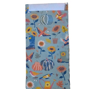 May include: A blue fabric panel with a white border and a repeating pattern of birds, flowers, and pumpkins. The pattern is in shades of orange, yellow, green, and brown.