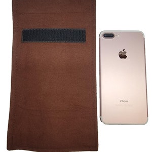 Op de afbeelding: Een bruine gevoerde tas met een zwarte klittenbandsluiting. De tas is ongeveer zo groot als een smartphone. De tas ligt naast een roze gouden iPhone.