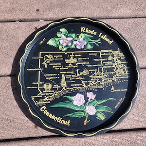Peut inclure: Plateau de service rond noir avec une carte du Rhode Island et du Connecticut, avec les noms des villes. Le plateau a un bord festonné avec une bordure dorée et des illustrations florales.