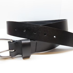 May include: A black leather belt with a silver buckle. The belt is folded in half and the buckle is on the left side of the image.