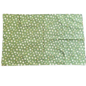 May include: A green fabric with a white daisy pattern. The fabric is folded in half.