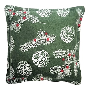 May include: A green throw pillow with a white pine cone and branch pattern. The pillow has a red berry design on the branches.