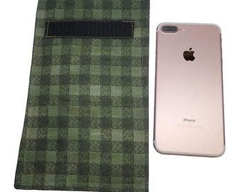 May include: A green and black checkered phone sleeve with a black velcro strap is next to a rose gold iPhone. The sleeve is rectangular and appears to be made of fabric. The iPhone has a silver camera and the Apple logo.