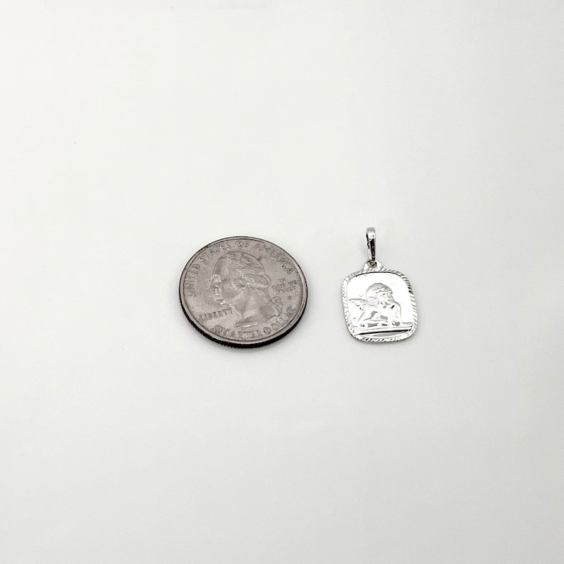 May include: Silver charm pendant featuring a detailed angel design. The pendant is approximately the size of a US quarter.