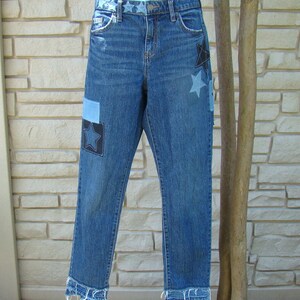 May include: Blue denim jeans with frayed hems and black star patches.