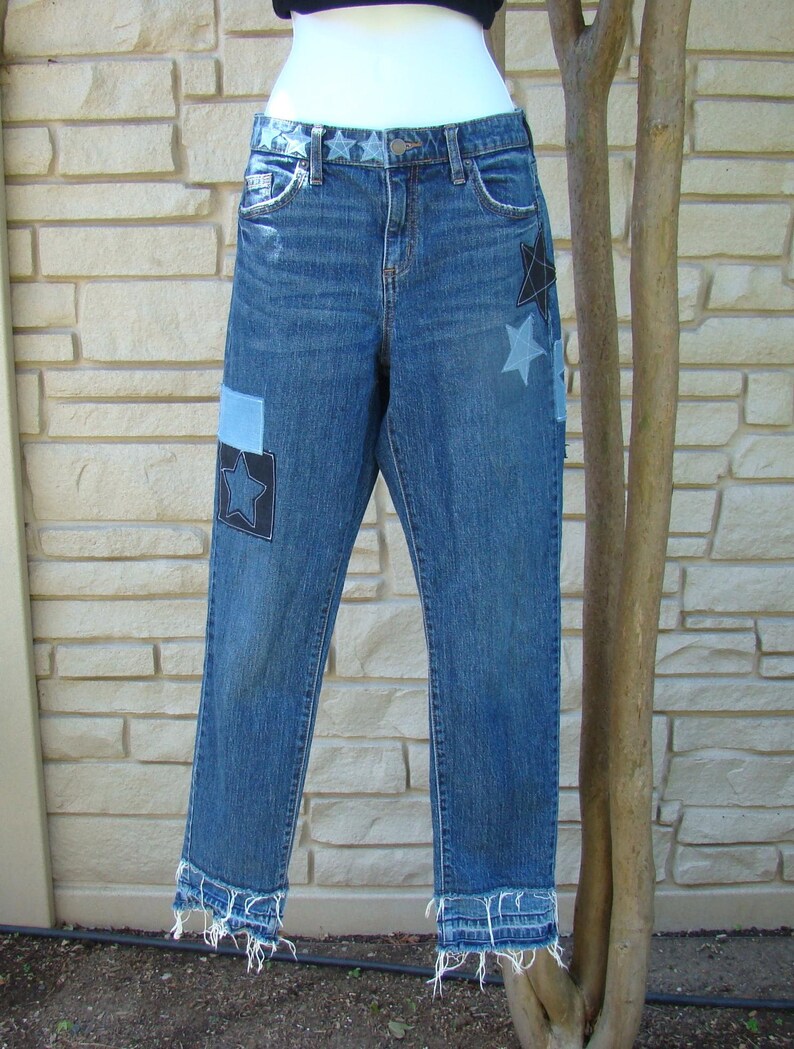 May include: Blue denim jeans with frayed hems and black star patches.