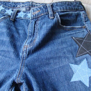 May include: Blue denim jeans with a black and a blue star patch sewn on the back pockets.