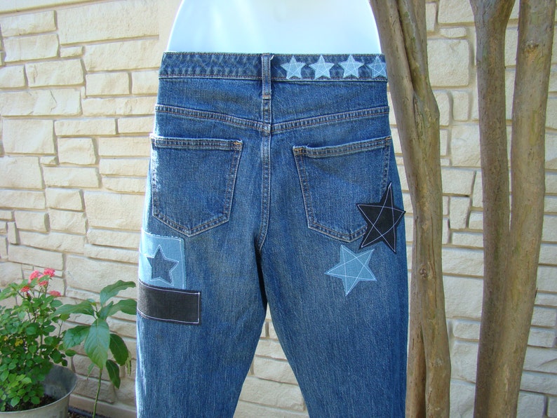 May include: Blue denim jeans with a black and blue star patch on the back pocket and a row of blue stars across the waistband.