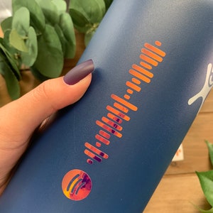 May include: A blue reusable water bottle with a metallic gold Spotify logo and a barcode-like design.