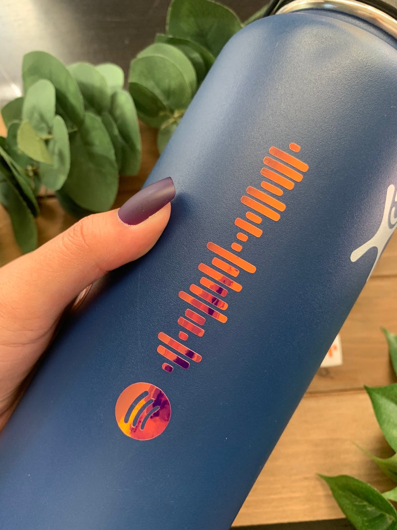 May include: A blue reusable water bottle with a metallic gold Spotify logo and a barcode-like design.