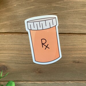 May include: A white sticker with a cartoon illustration of a pill bottle with a white lid and the letter "Rx" on the label.