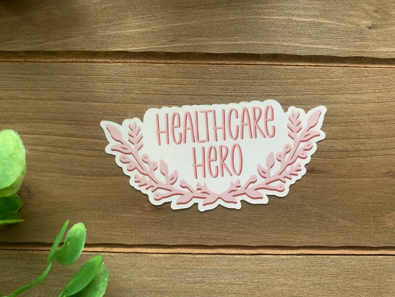 May include: Pink sticker with a floral wreath design and the text "Healthcare Hero".