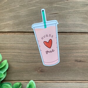 May include: A pink and white sticker of a coffee cup with a green straw. The cup has the text "Nurse Fuel" and a red heart.