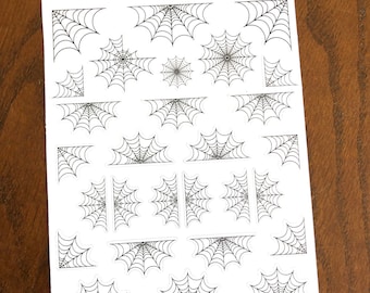 May include: A sheet of white sticker paper with black spiderweb designs. The sheet has the text "Peanut Butter Taco" at the top.
