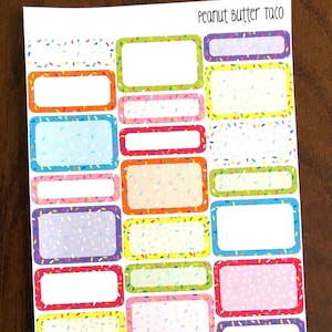 May include: A sheet of colorful rectangular labels with a sprinkle pattern. The labels are blank and ready to be used for organizing and labeling. The text "Peanut Butter Taco" is at the top of the sheet.