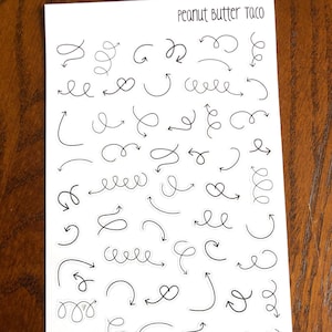 May include: A sheet of white paper with black doodle arrow stickers. The sheet has the text "Peanut Butter Taco" at the top.