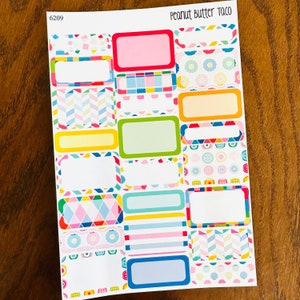 May include: A sheet of colorful planner stickers with various patterns and designs. The stickers are rectangular and have blank spaces for writing. The sheet is labeled "Peanut Butter Taco" and "6209".
