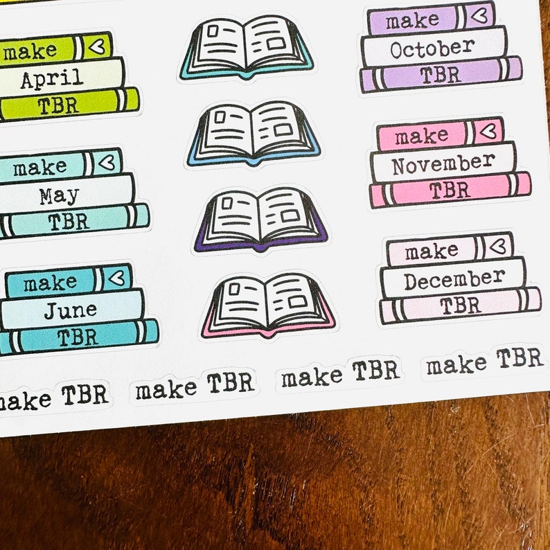 May include: A set of colorful stickers featuring stacks of books with the text "make" and the months of April, May, June, October, November, and December. The stickers also include open book illustrations in various colors.